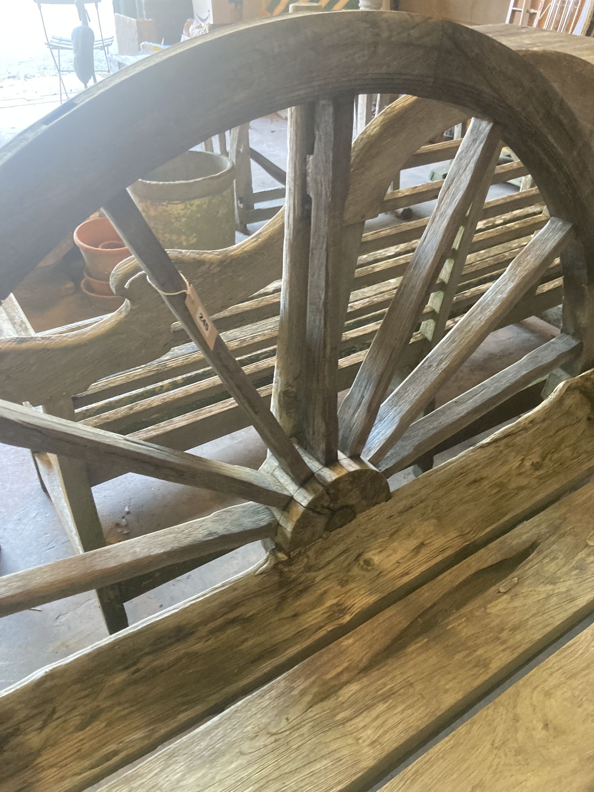 A weathered hardwood cartwheel garden bench, width 140cm depth 70cm height 116cm
